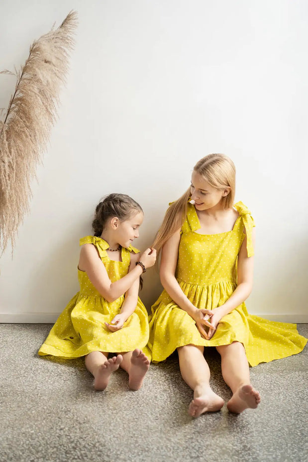 Bright yellow, sleeveless dresses with delicate polka dots and tied shoulder straps.